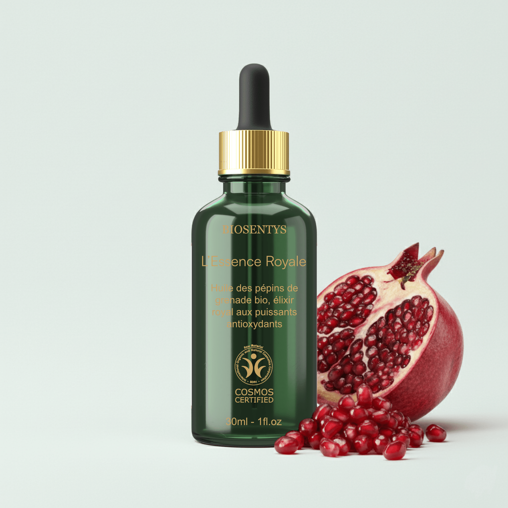 Essence Royale — Huile des pépins de grenade Bio – BIOSENTYS | Flacon vert foncé avec pipette d'Essence Royale — Huile des pépins de grenade Bio près d'une grenade ouverte et graines rouges.